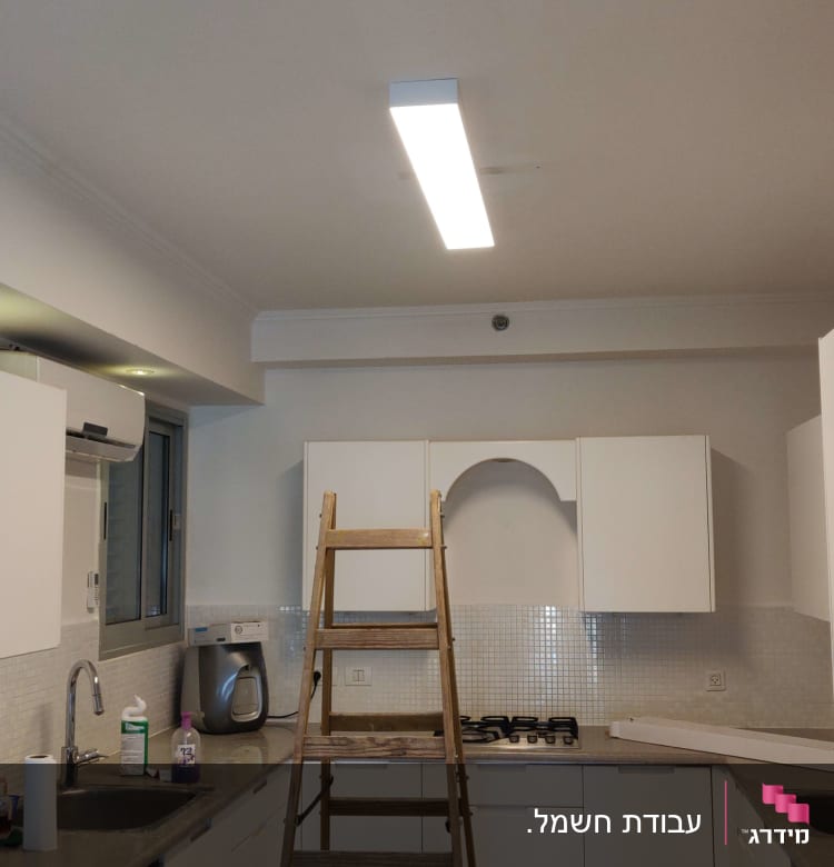 סולם עץ מתחת לגוף תאורה בתקרה